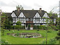 Pond, green and mock-Tudor house