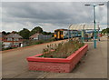 Flowerbed, shelter and train at Grangetown railway station, Cardiff