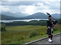 NN3045 : Loch Tulla: a view and a piper by Chris Downer