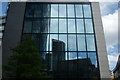 View of the reflection of the towerblock on Camomile Street and the Gherkin in the building on Bury Court