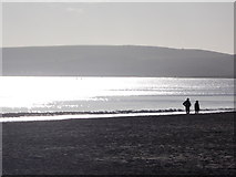 SZ0588 : Canford Cliffs: silhouetted walkers on the beach by Chris Downer