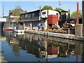 TQ2083 : Canal-side yard with caravan as office by David Hawgood