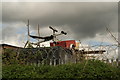 View of a gym bench and trailer on the roof of a container at the rear of Redbridge Garden Centre from Salix Lane