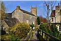 Nunney: All Saints Church: The church from the little bridge over the river