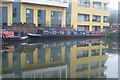 View of an office block on Oval Road and one of the Pirates Club houseboats reflected in the Regents Canal