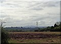 Muddy field, pylon and distant Malvern Hills