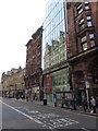 The glass of Sixty7 reflecting older buildings