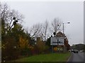 Road direction sign and assorted adverts, A38, east of Taunton