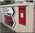 Queen Elizabeth II postbox and direction signs on a Paignton wall