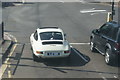 View of a Porsche 911 waiting at the traffic lights at Eltham station from the top deck of a 132 bus on Well Hall Road