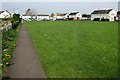 Path past the edge of a green in Stonehouse