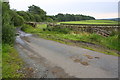 Minor road passing field gateways going towards Higher Green Wood