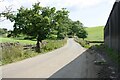 Looking south along rural road passing farm near Stainton Hall