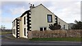 Hunters Cottage beside minor road approaching A686