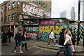 View of street art on the side of a hut and the parade of shops on Brick Lane