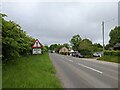 Warning sign, cars and buildings on the old A30, heading west