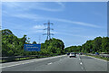 On the M4 westbound, signs for services and power lines next to the motorway