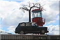 View of a black cab with a tree on its roof on top of The Orchard cafe in Trinity Buoy Wharf