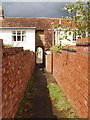 Footpath through archway between stone houses, Podington