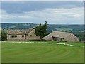 View over cricket pitch towards converted barn